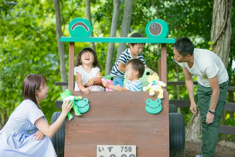 Une famille joue autour d'une structure en bois décorée de grenouilles.