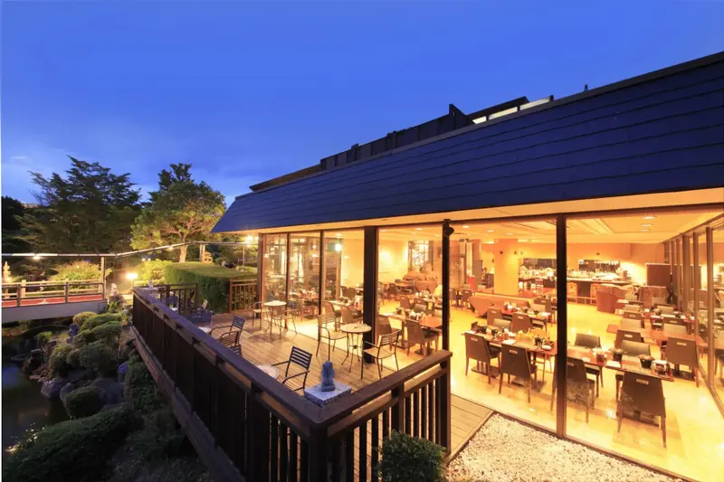 Terrasse lumineuse donnant sur un jardin soigné au crépuscule.