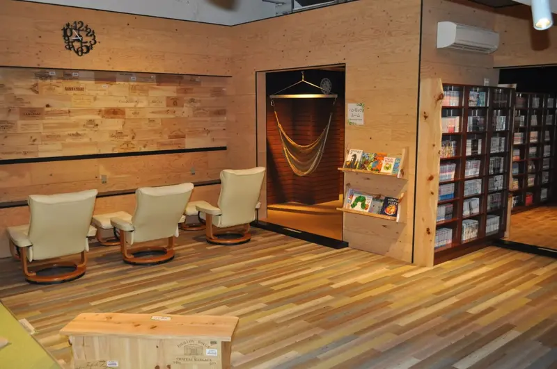 Espace de détente avec des fauteuils et une bibliothèque en bois.