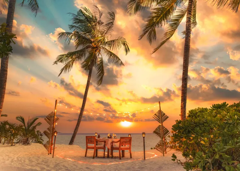 Une table dressée sur une plage au coucher du soleil.