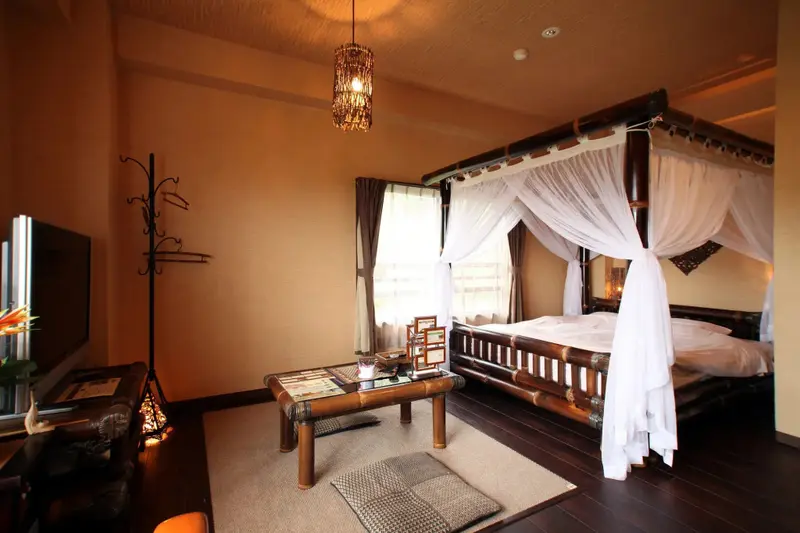 Une chambre à coucher avec un lit à baldaquin en bois et une décoration exotique.