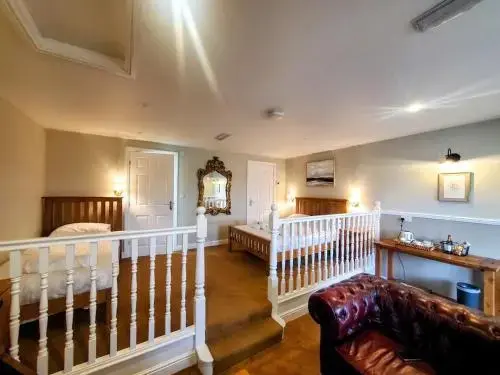 Une chambre lumineuse avec deux lits simples et un canapé en cuir.