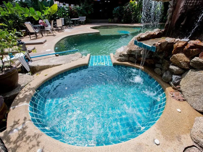 Piscine avec jacuzzi intégré et cascade artificielle.