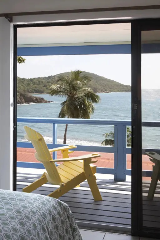 Une terrasse ensoleillée offre une vue sur la mer et la végétation tropicale.