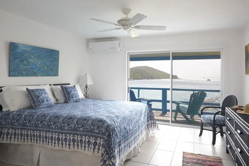 Une chambre lumineuse avec un grand lit donnant sur une vue mer.