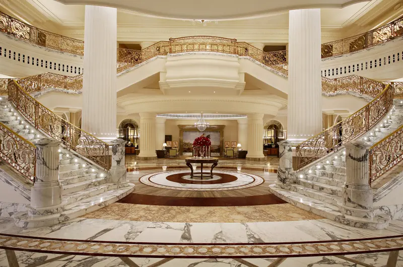 Vaste hall d'entrée avec deux escaliers en marbre et une décoration opulente.
