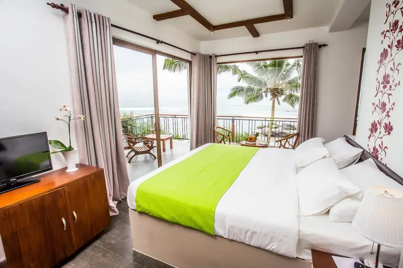 Une chambre lumineuse avec un grand lit donnant sur une vue mer.