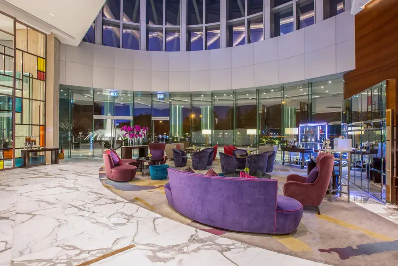 Un espace de détente intérieur avec des fauteuils et canapés violets et roses.