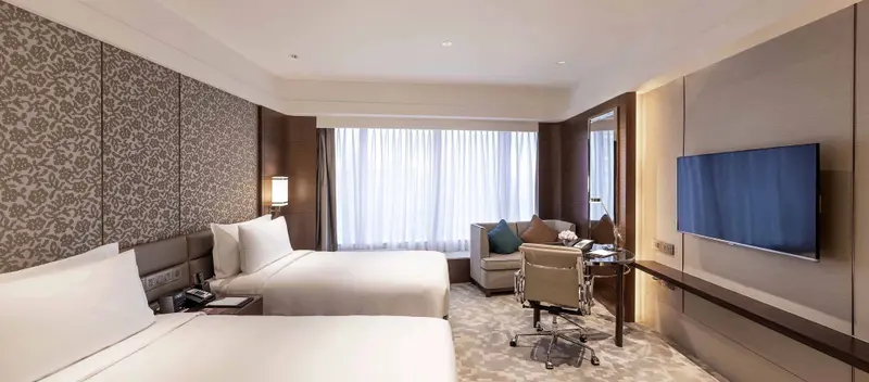 Une chambre lumineuse avec deux lits et un espace bureau.