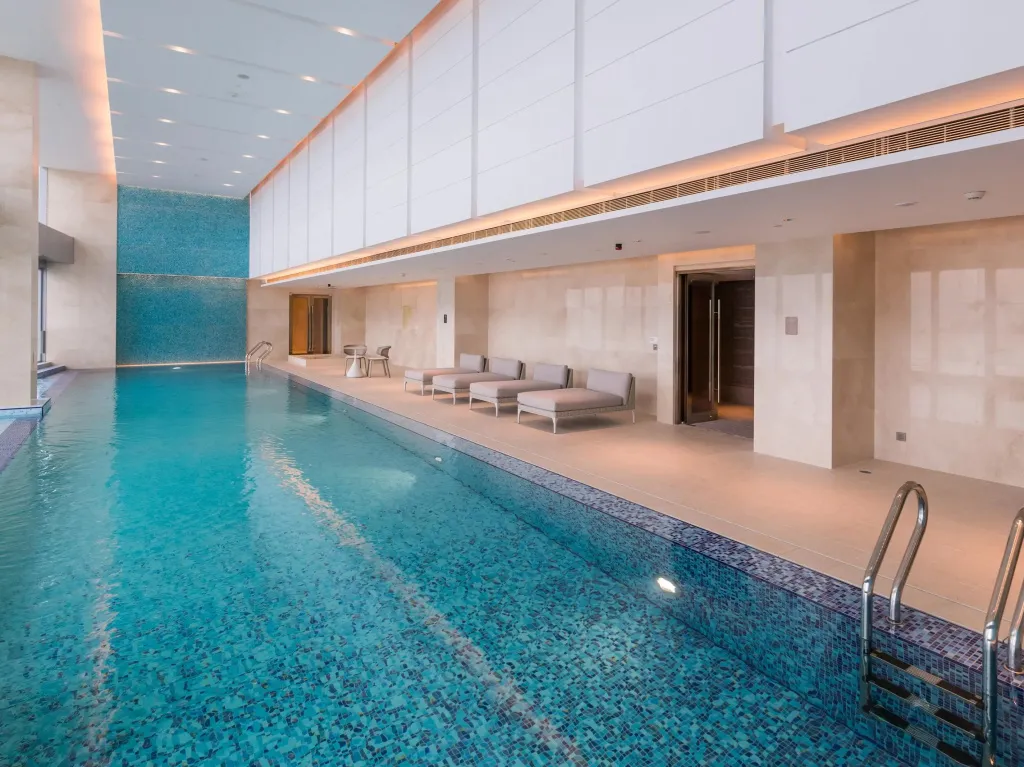 Une piscine intérieure lumineuse avec des transats alignés le long du bord.