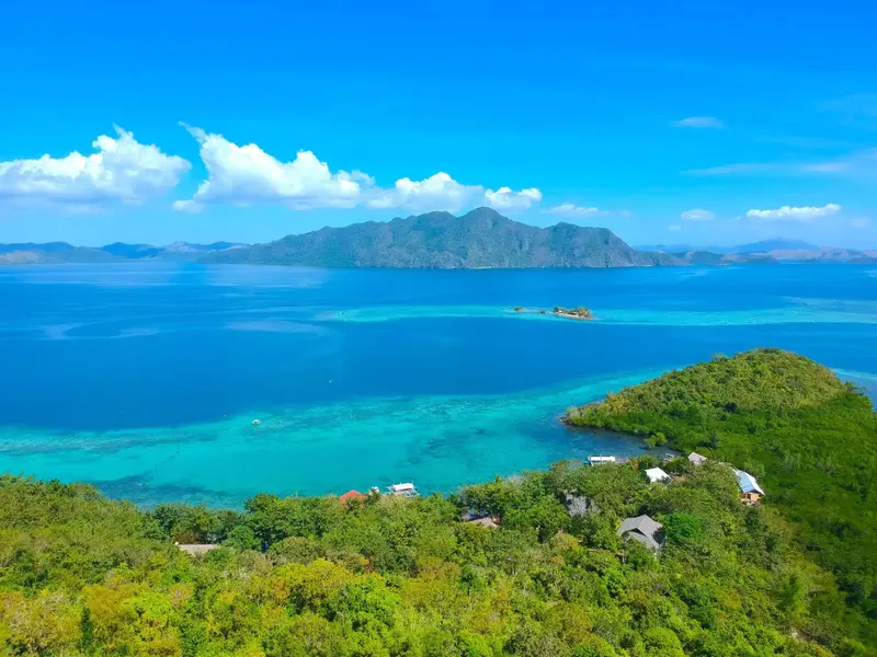 Vue aérienne d'une côte tropicale avec des bâtiments au milieu de la végétation.