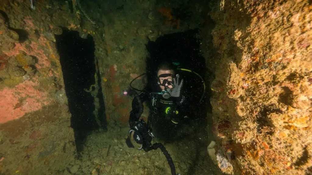 Un plongeur explore une grotte sous-marine rocheuse.