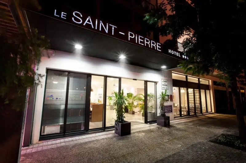 Façade d'hôtel illuminée la nuit avec une entrée vitrée.