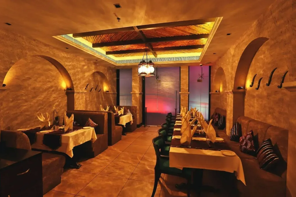 Une salle de restaurant à l'ambiance chaleureuse avec des tables dressées et des luminaires décoratifs.