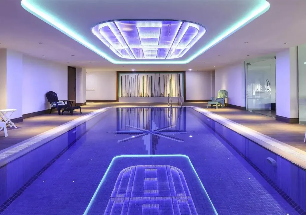 Une piscine intérieure rectangulaire illuminée de couleurs vives.