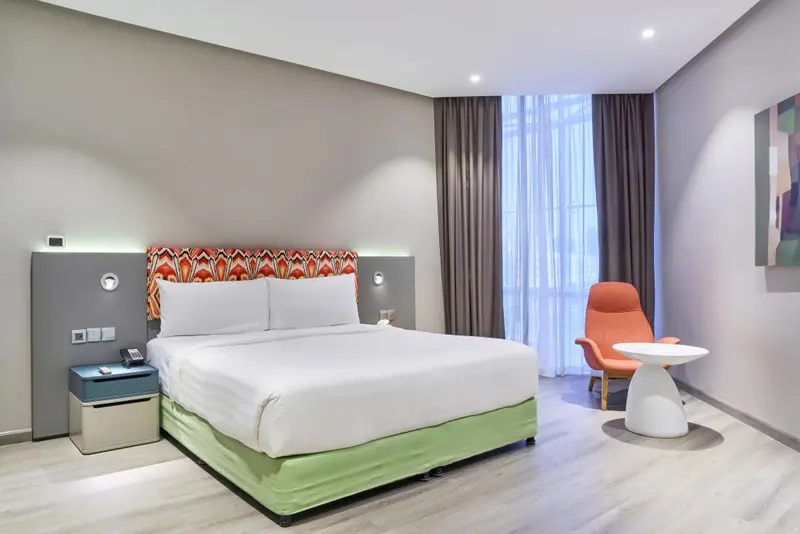 Une chambre lumineuse avec un grand lit et un fauteuil.
