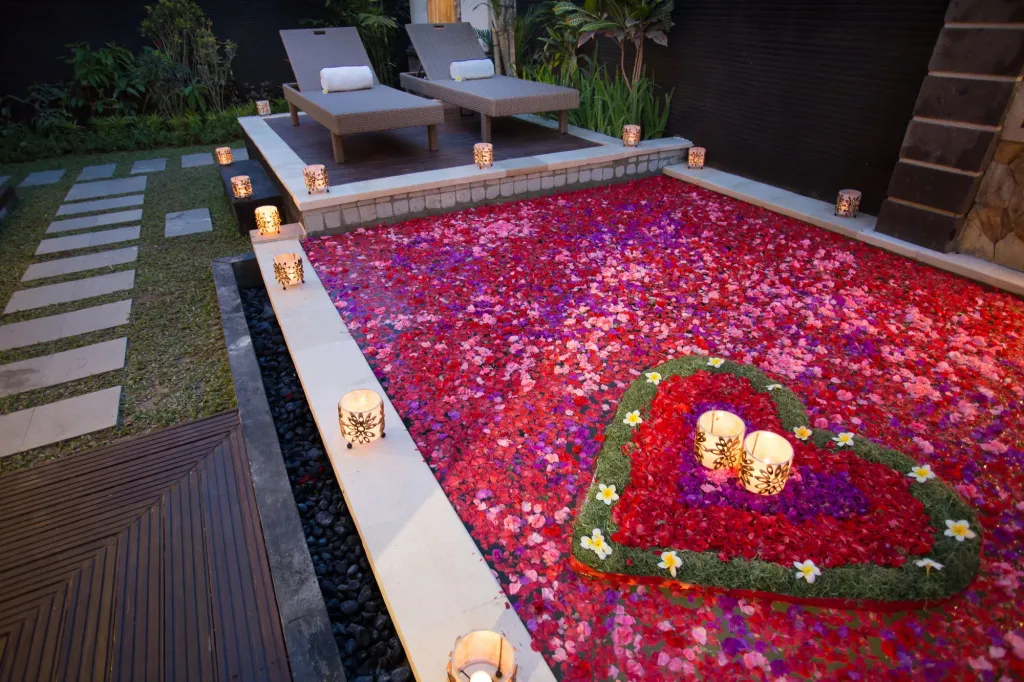 Deux chaises longues invitent à la détente au bord d'une piscine couverte de pétales de fleurs.