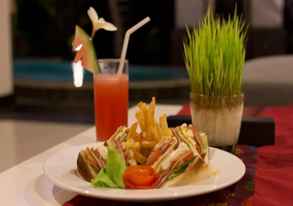 Un plat composé de sandwich, de frites et d'une boisson fruitée est présenté sur une table.