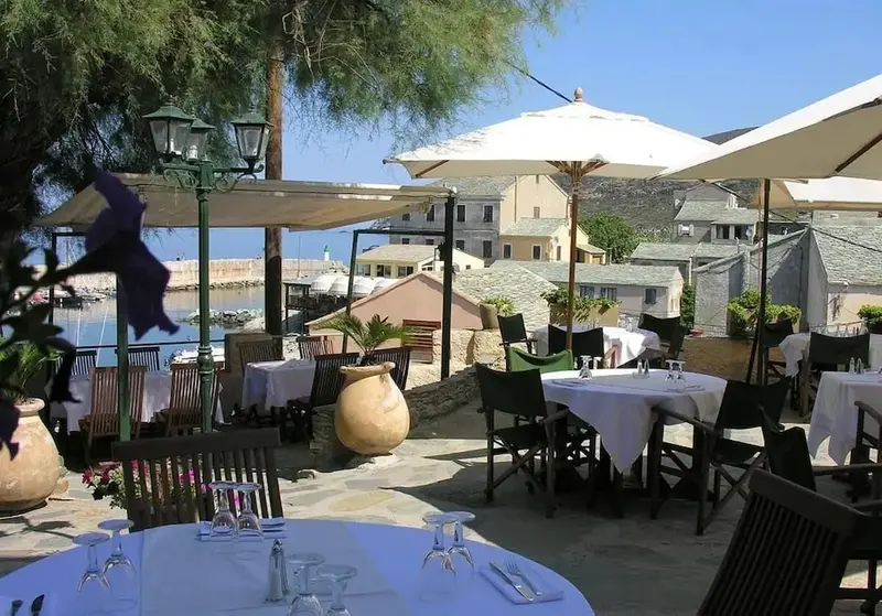 Tables dressées en terrasse avec vue sur le port et les bâtiments environnants.