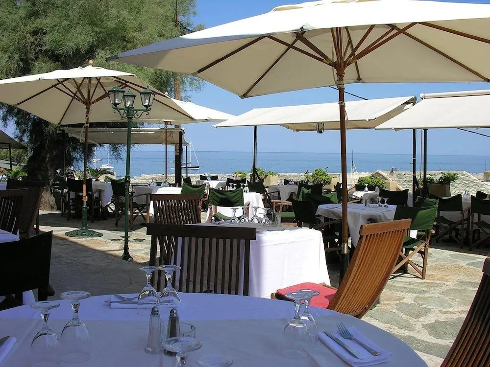Tables dressées à l'extérieur sous des parasols avec vue sur la mer.