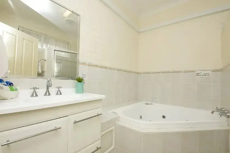 Une salle de bain lumineuse avec baignoire d'angle et meuble vasque.