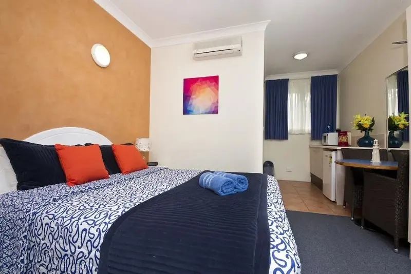 Une chambre lumineuse avec un grand lit et un coin repas.