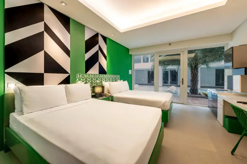 Une chambre lumineuse avec deux lits et un accès à une terrasse.