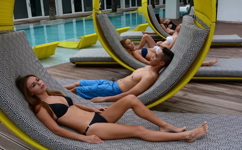 Des personnes se relaxent sur des chaises longues au bord d'une piscine.