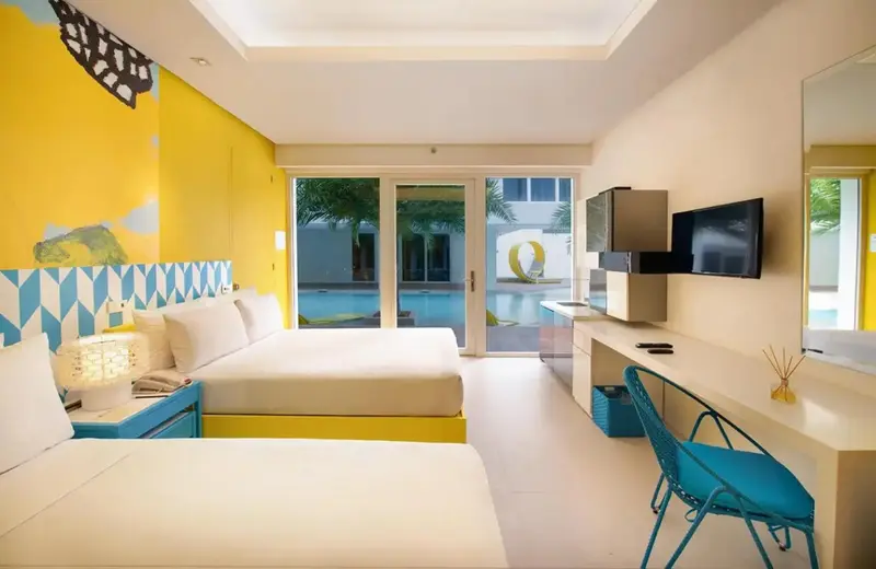Une chambre lumineuse avec deux lits et vue sur une piscine.
