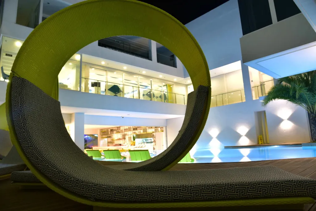 Transats design au bord d'une piscine illuminée la nuit.