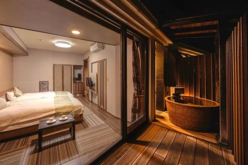 Une chambre à coucher s'ouvre sur un bain extérieur en bois.
