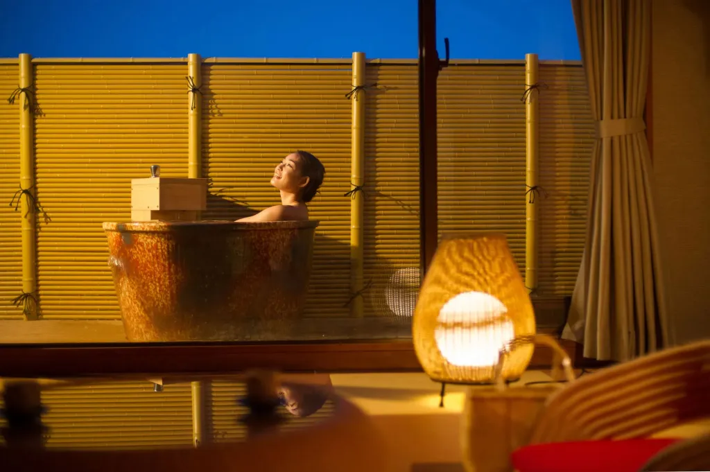 Une femme se détend dans un bain extérieur sur une terrasse.