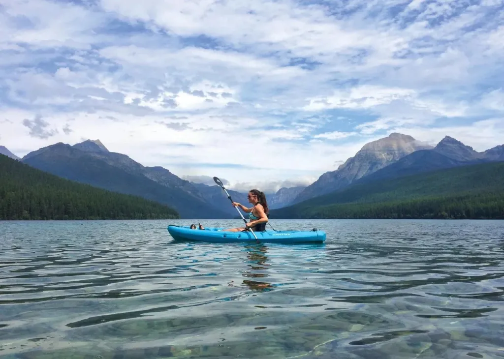 Une personne pratique le kayak sur un lac de montagne.