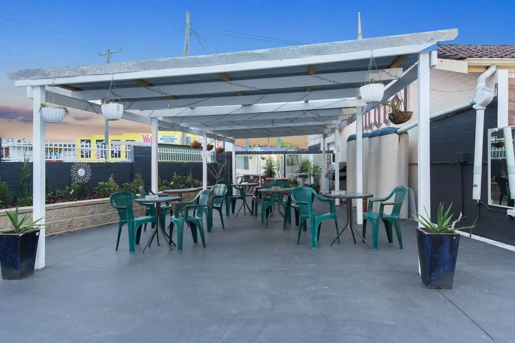 Terrasse ombragée avec tables et chaises vertes.