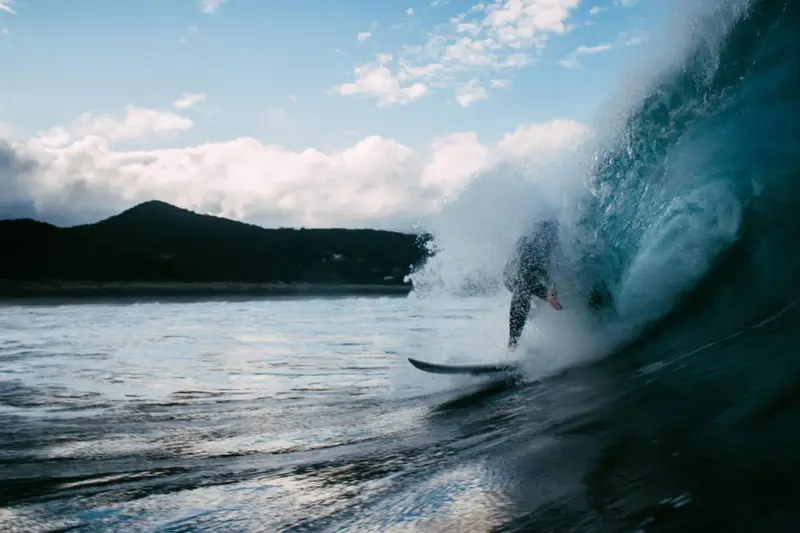Un surfeur chevauche une vague puissante dans une eau turquoise.