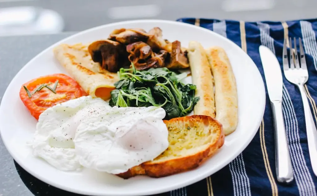 Assiette copieuse avec oeufs pochés, légumes verts, champignons et pain grillé.