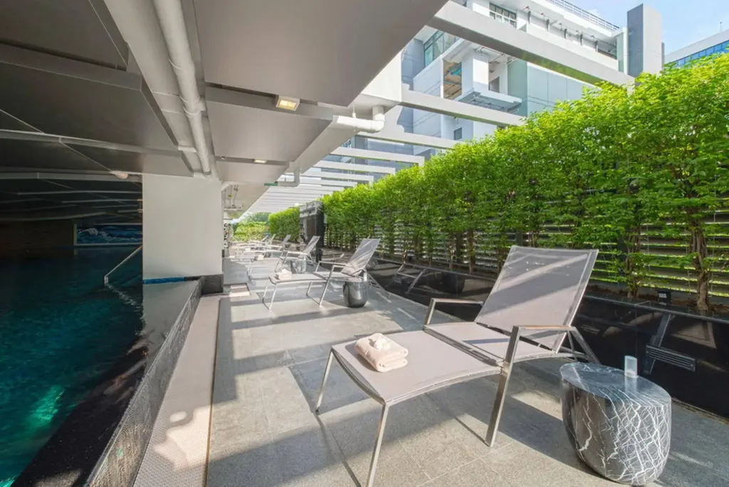 Transats alignés sur une terrasse ombragée près d'une piscine.