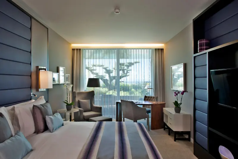Une chambre lumineuse avec un grand lit et un espace détente près d'une fenêtre.