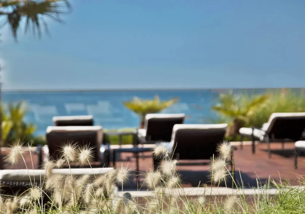 Transats alignés sur une terrasse en bois avec vue sur la mer.