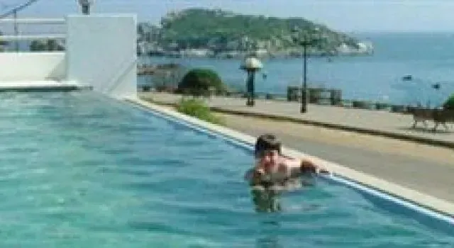 Une personne se trouve dans une piscine avec vue sur la mer et une île.