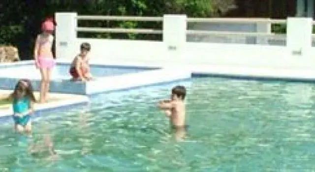 Des enfants s'amusent dans une piscine ensoleillée.