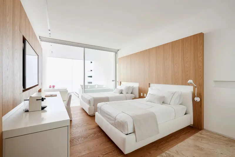 Une chambre lumineuse avec deux lits simples et un bureau.