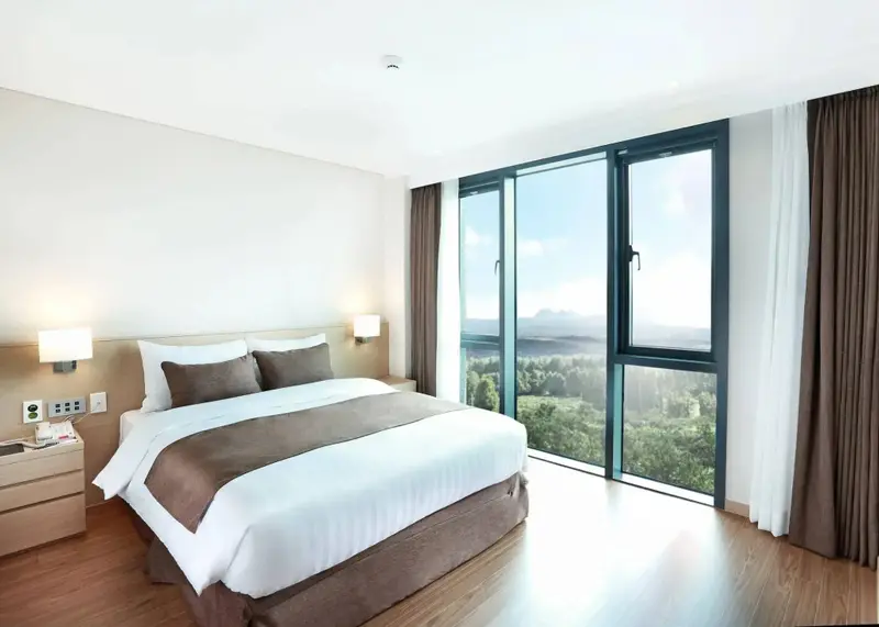 Une chambre lumineuse avec un grand lit et une vue sur un paysage verdoyant.