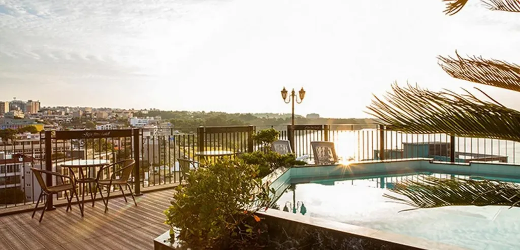 Terrasse avec mobilier de jardin et piscine au bord de l'eau, avec une vue sur la ville.