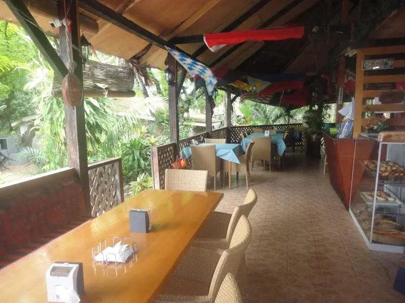Une salle à manger extérieure avec des tables en bois et des chaises en rotin.