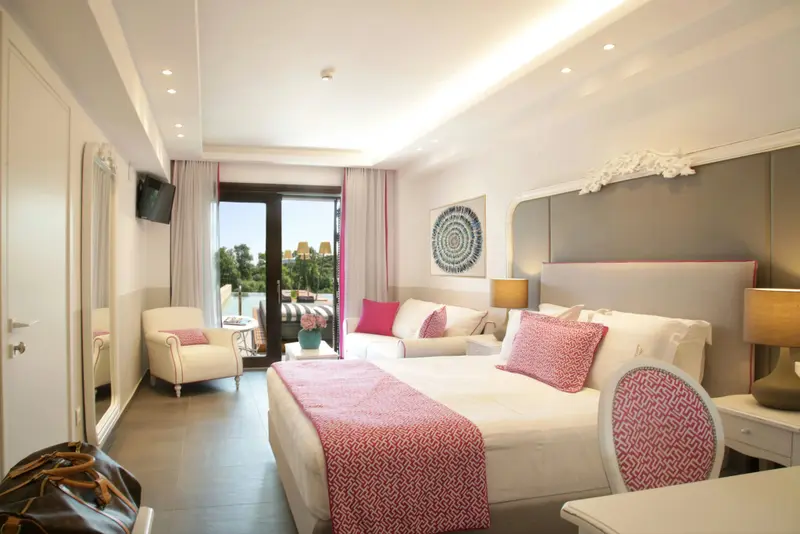 Une chambre lumineuse avec un lit fait et un coin salon.