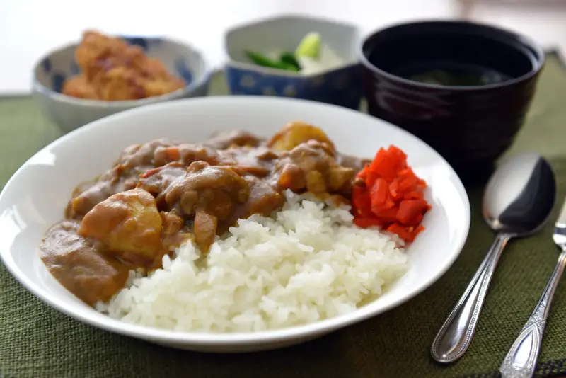 Un plat de riz au curry japonais est servi avec des accompagnements.