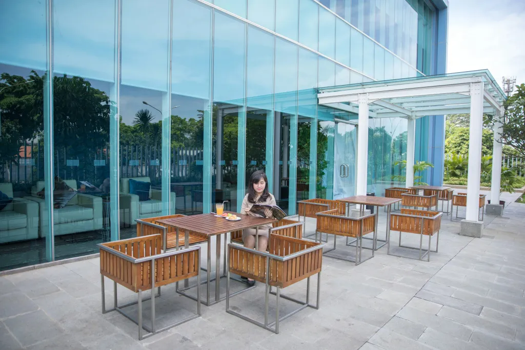 Une personne est assise à une table sur une terrasse ombragée.