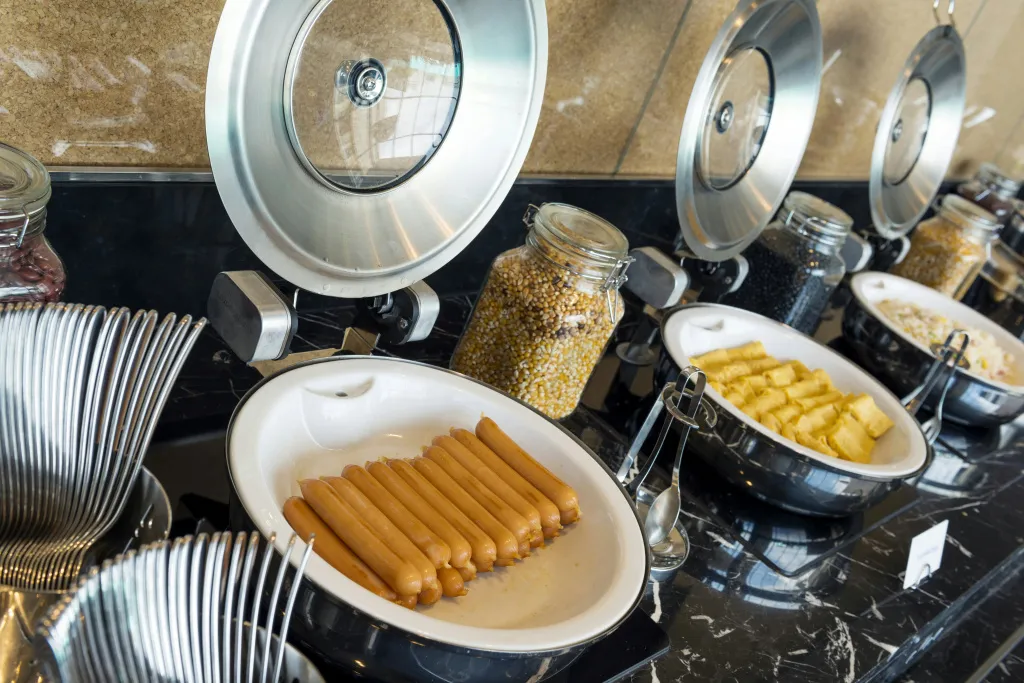 Un buffet propose des céréales, des fruits et de la charcuterie.
