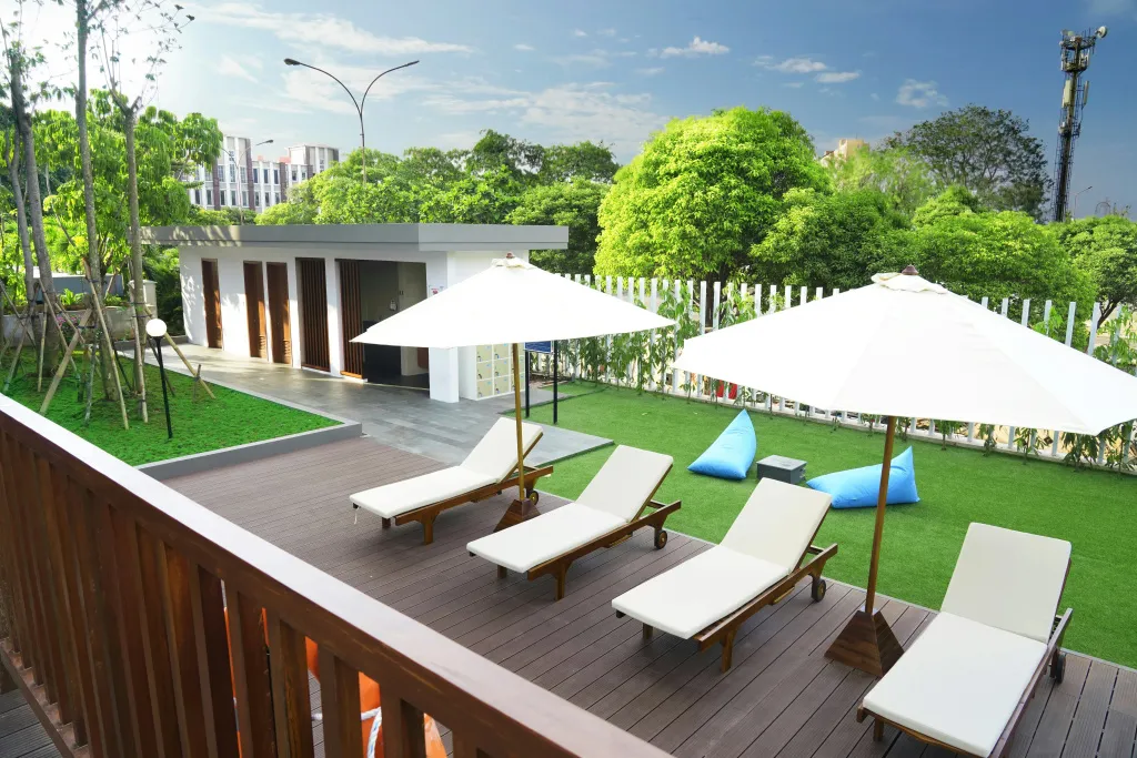 Terrasse aménagée avec des transats et des parasols blancs, surplombant un espace vert.